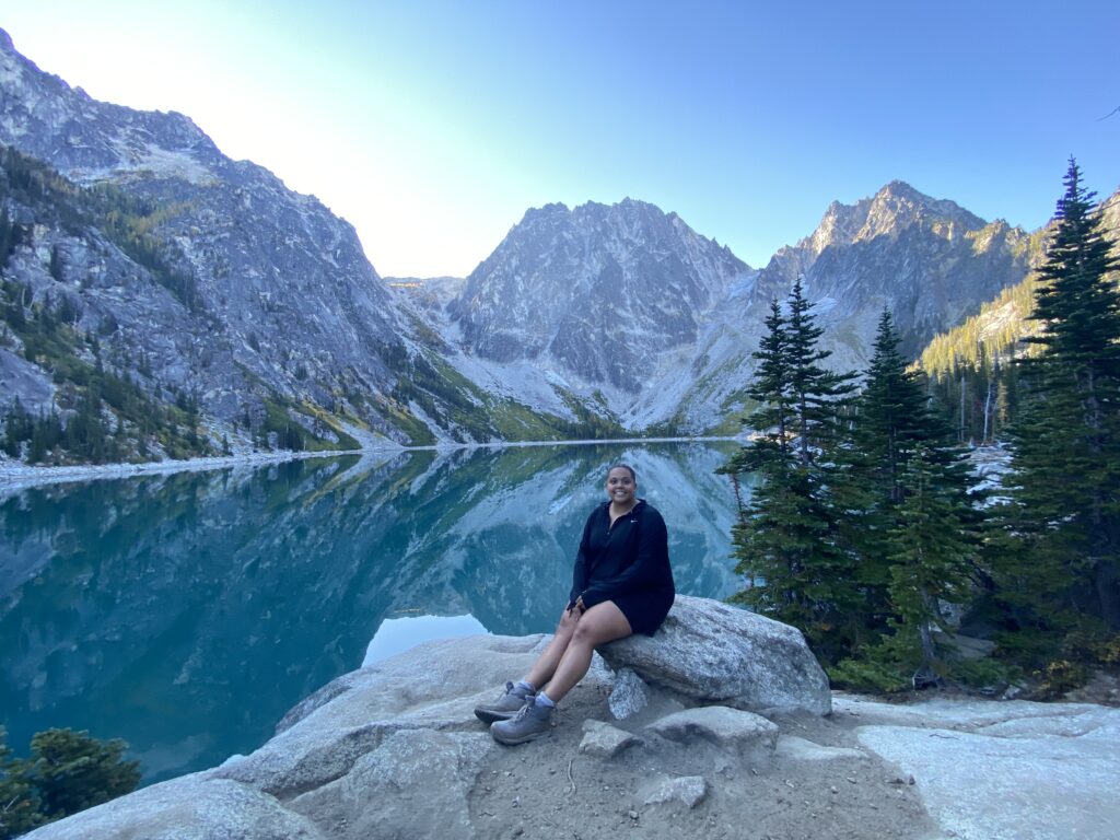 A woman sitting on a rock in front of a mountain lake.