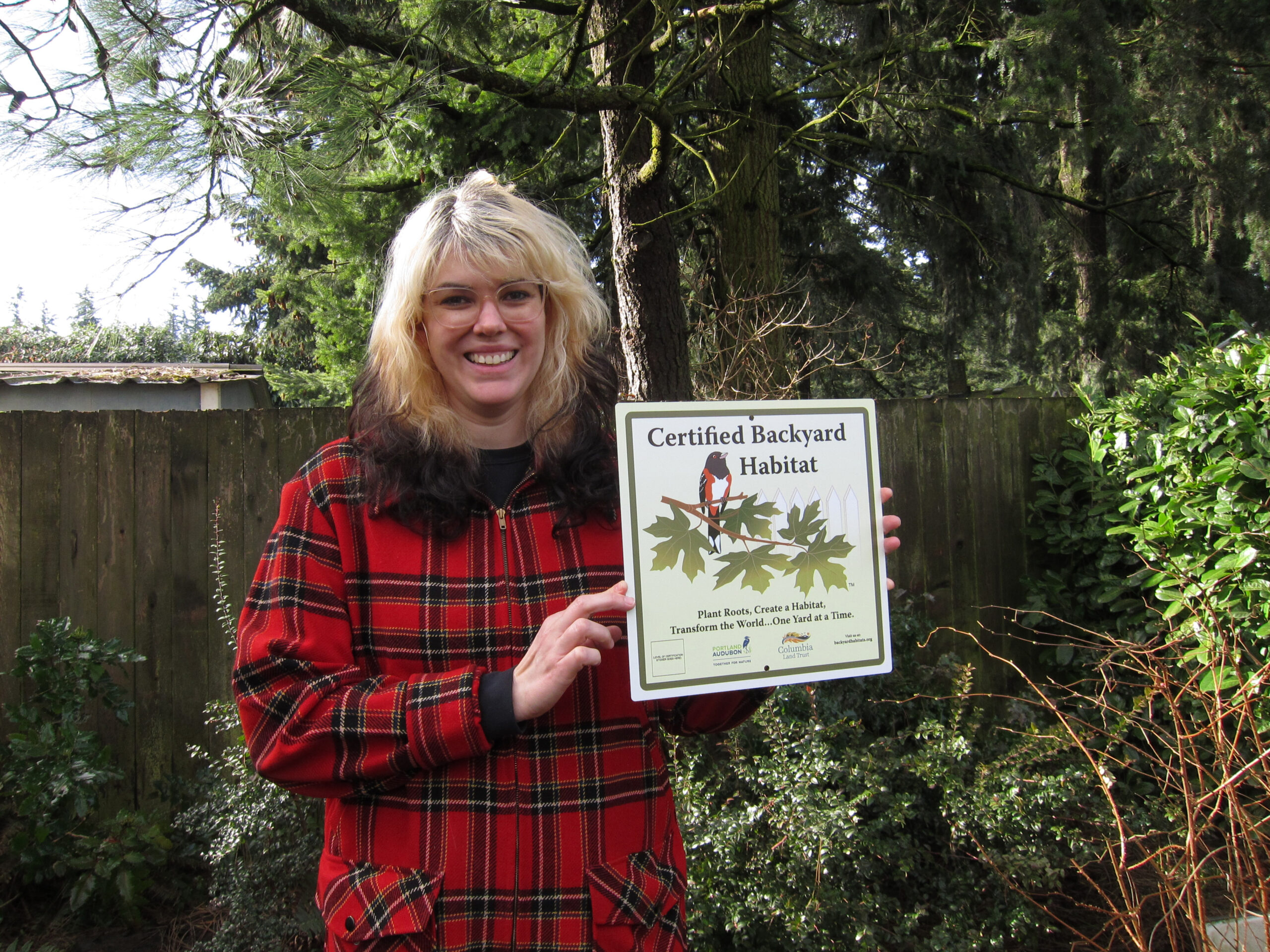 A woman in a plaid coat holding a sign.